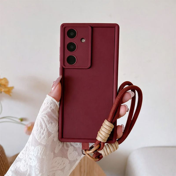 Red phone case with a strap held by a hand against a light background